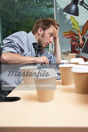Man Working at Desk with Coffee Cups