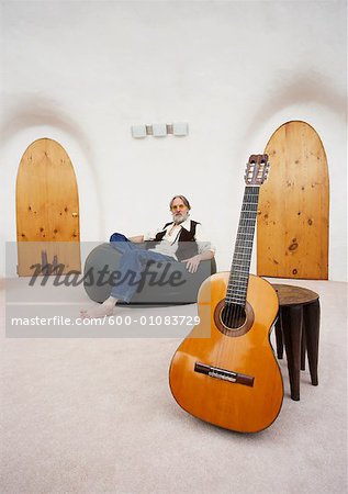 Man Sitting in Bean Bag Chair with Guitar in Foreground