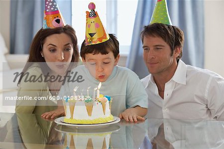 Boy Blowing out Birthday Candles with Parents