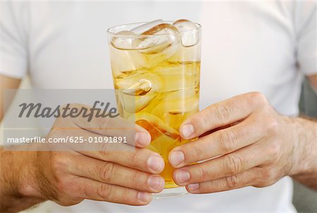 Mid section view of a man holding a glass of whiskey