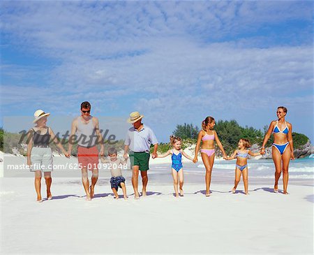 Famille de trois générations marchant sur la plage avec la main dans la main, Bermudes