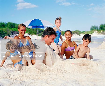 Gros plan d'un milieu couple adult assis avec leurs enfants sur la plage, Bermudes