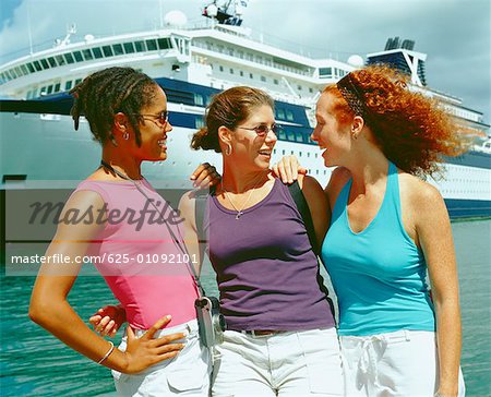 Close-up of three young women standing on the beach in front of a cruise ship, Bermuda