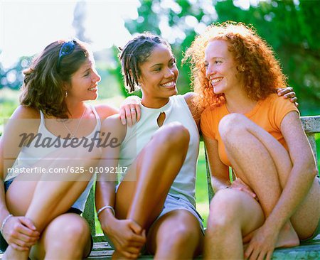 Gros plan de trois jeunes femmes assises sur un banc et souriant, Bermudes
