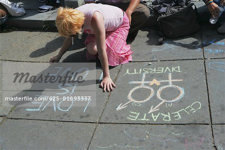 High angle view of a lesbian woman writing messages with a chalk on the road