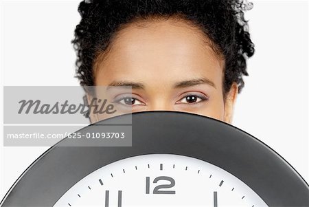 Portrait d'une femme d'affaires cachant son visage derrière une horloge