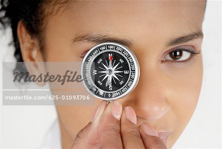 Portrait of a businesswoman covering her eye with a compass