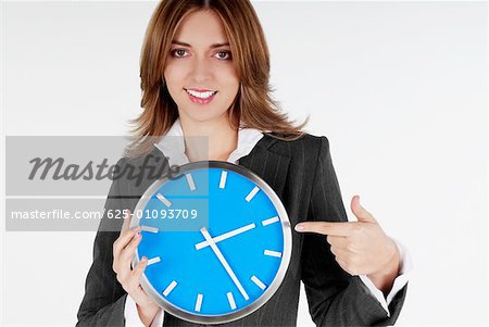 Portrait of a businesswoman pointing at a clock and smiling