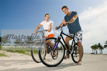 Portrait de deux jeunes hommes détenant des bicyclettes