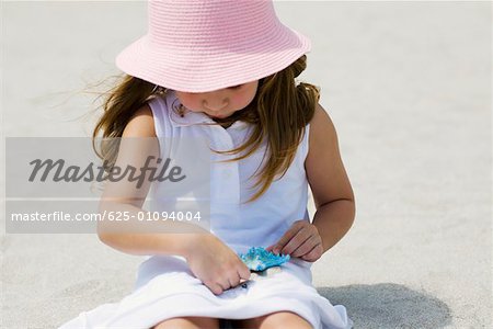 Close-up of a girl playing with a starfish on the beach