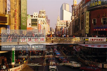 Masse der Leute auf einer Fußgängerbrücke über einer Straße, China