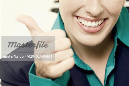 Close-up of a businesswoman showing thumbs up sign and smiling