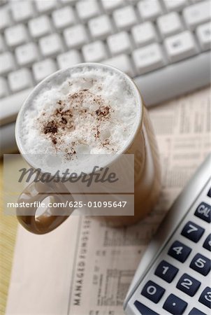 High angle view of a coffee cup with a computer keyboard and a calculator