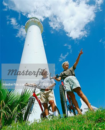 Vue d'angle faible d'un couple supérieur devant une tour avec leur vélo, Bermudes