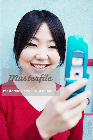 Close-up of a young woman holding a mobile phone and smiling