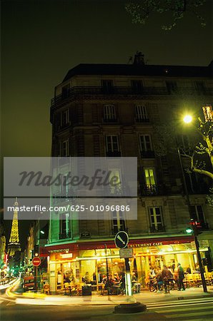 Gebäude vor einem Turm beleuchtet bei Nacht, Eiffelturm, Paris, Frankreich