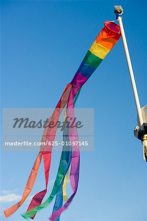 Low angle view of gay pride flag fluttering on a pole