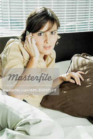Portrait of a mid adult woman talking on a mobile phone on the bed