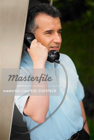 Close-up of a mid adult man talking on a pay phone