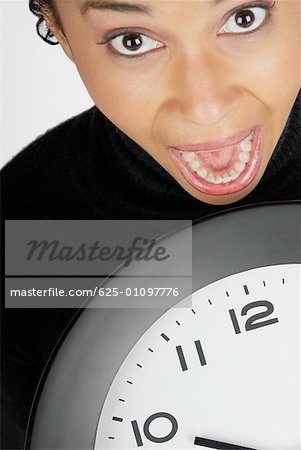 Portrait of a businesswoman holding a clock with her mouth open