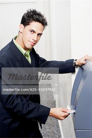 Portrait of a businessman inserting a credit card into an ATM