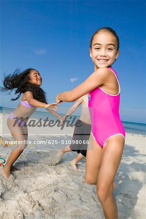 Zwei Mädchen und Jungen spielen am Strand