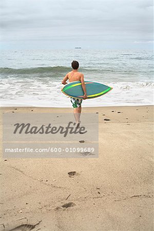 Man Carrying Surfboard into Water