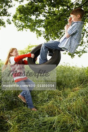Girl and Boy Playing with Tire Swing
