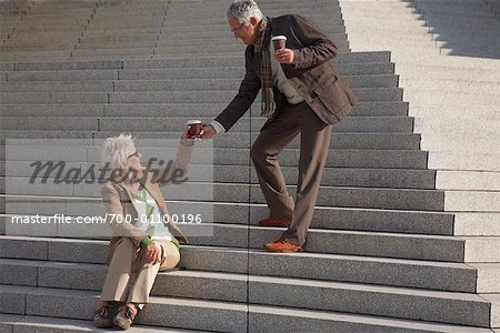 Man Giving Coffee to Woman Sitting on Steps
