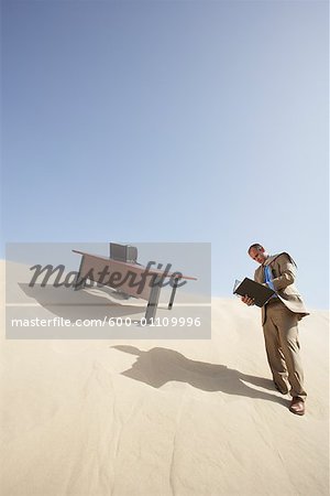 Homme d'affaires de lecture du fichier de bureau dans le désert