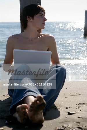 Homme utilisant un ordinateur portable à la plage