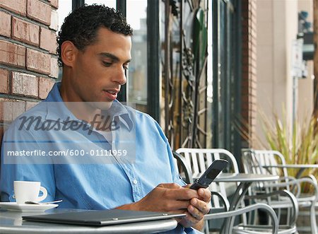 Homme assis à la Table de café et l'utilisation des téléphones cellulaires