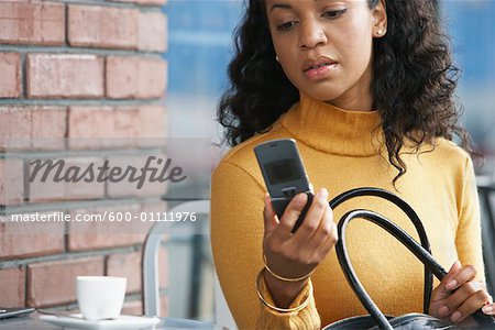 Woman sitting at Cafe Table Looking at Cellular Phone