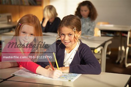 Portrait de jeunes filles assis à un bureau en salle de classe