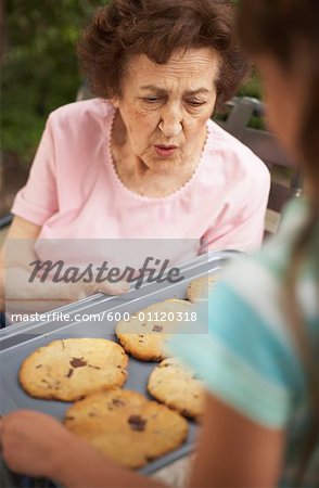 Grand-mère montrant petite-fille plateau de biscuits maison