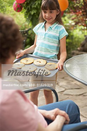 Granddaughter Showing Grandmother Tray of Homemade Cookies