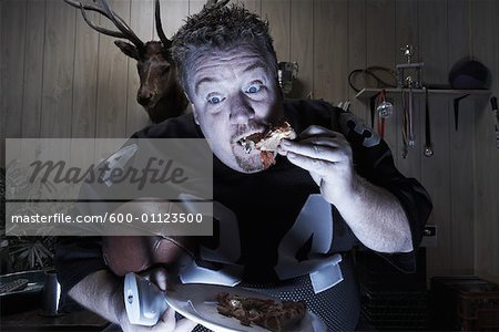 Homme, regarder la télévision et manger des pizzas