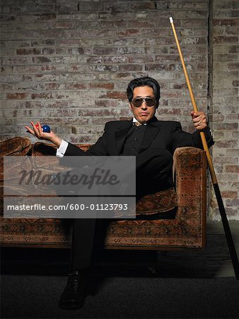 Portrait of Man on Sofa with Pool Cue and Billiard Balls
