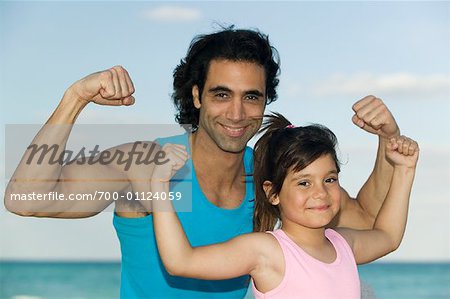 Portrait of Father and Daughter Flexing Muscles
