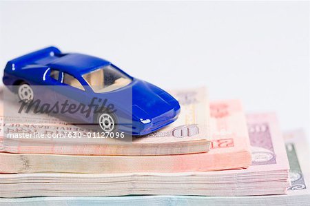 Close-up of a toy car on a stack of Indian banknotes of different denominations