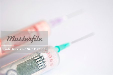 Close-up of Indian banknotes of different denominations inside two syringes