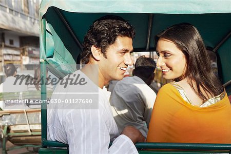 Close-up of a young couple sitting in a rickshaw looking at each other