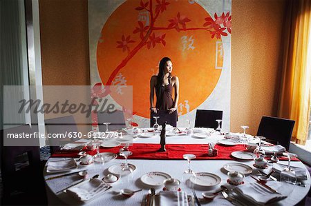 Jeune femme debout derrière une table dans un restaurant