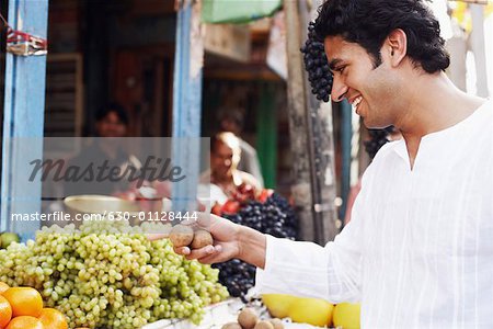 Profil de côté d'un jeune homme debout sur un stand de fruits