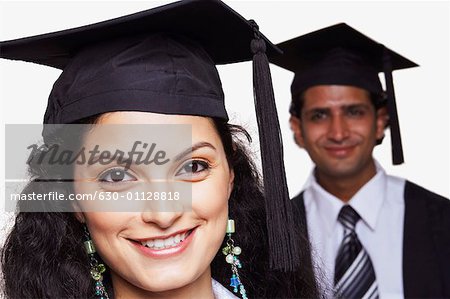 Portrait of a female graduate smiling with a male graduate behind her