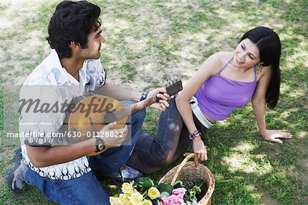 Vue grand angle d'un jeune homme jouant de la mandoline avec une jeune femme regardant