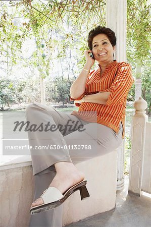 Femme mature assis sur le mur et de parler sur un téléphone mobile