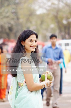 Portrait of a young woman holding a coconut and smiling