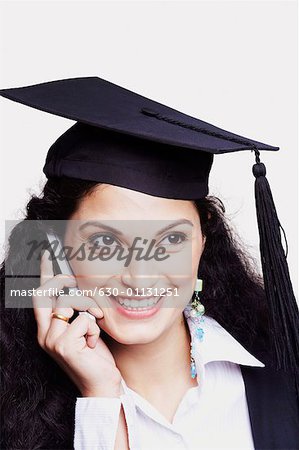 Close-up of a female graduate using a mobile phone and smiling