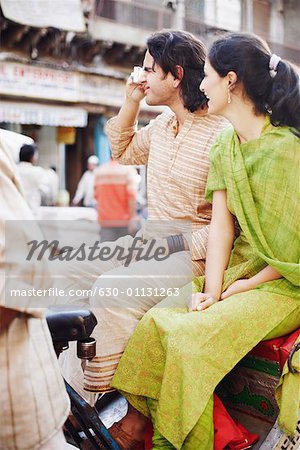 Profil de côté d'un jeune couple assis dans un pousse-pousse et prendre une photo